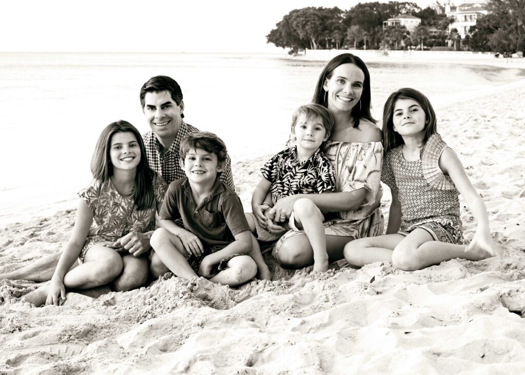 Family of six seated together on a Barbados beach