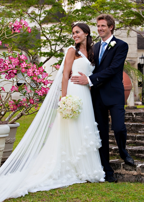 Newlyweds posing beside pink blossoms in a Barbados garden