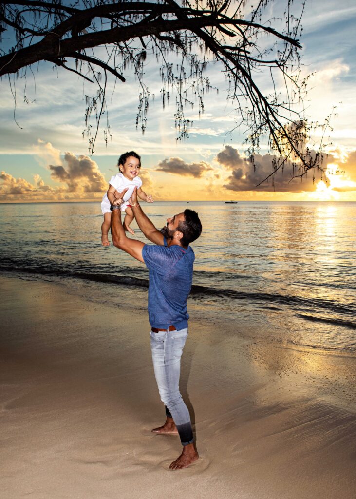 Father lifting his baby at sunset on a Barbados beach