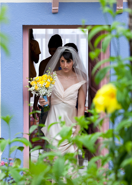 Bride stepping through a colorful doorway with her yellow wedding bouquet
