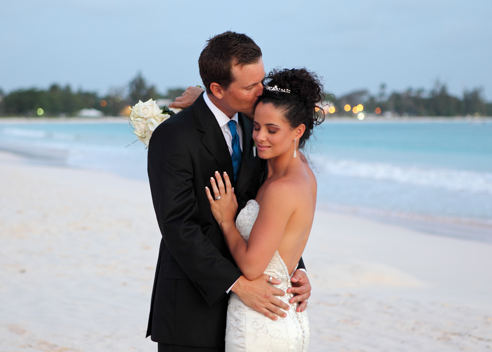 Groom kissing his bride during a Barbados beach wedding portrait
