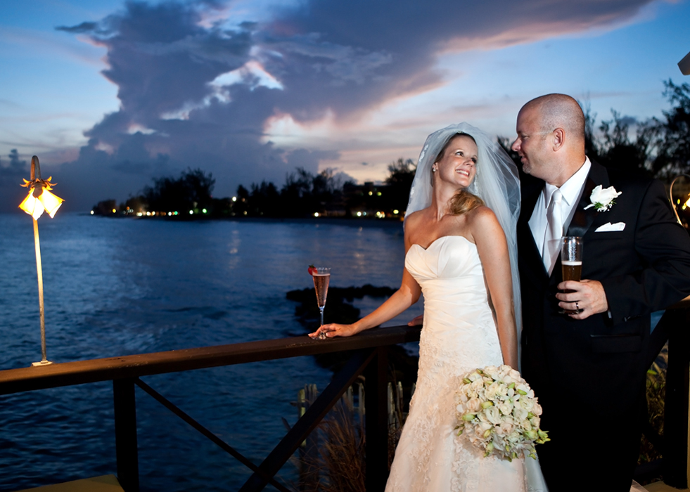 Newlyweds sharing a toast beside the water at their Barbados wedding reception