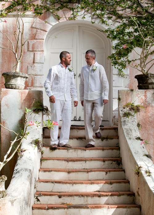 Two grooms walking down the steps of a historic Barbados venue