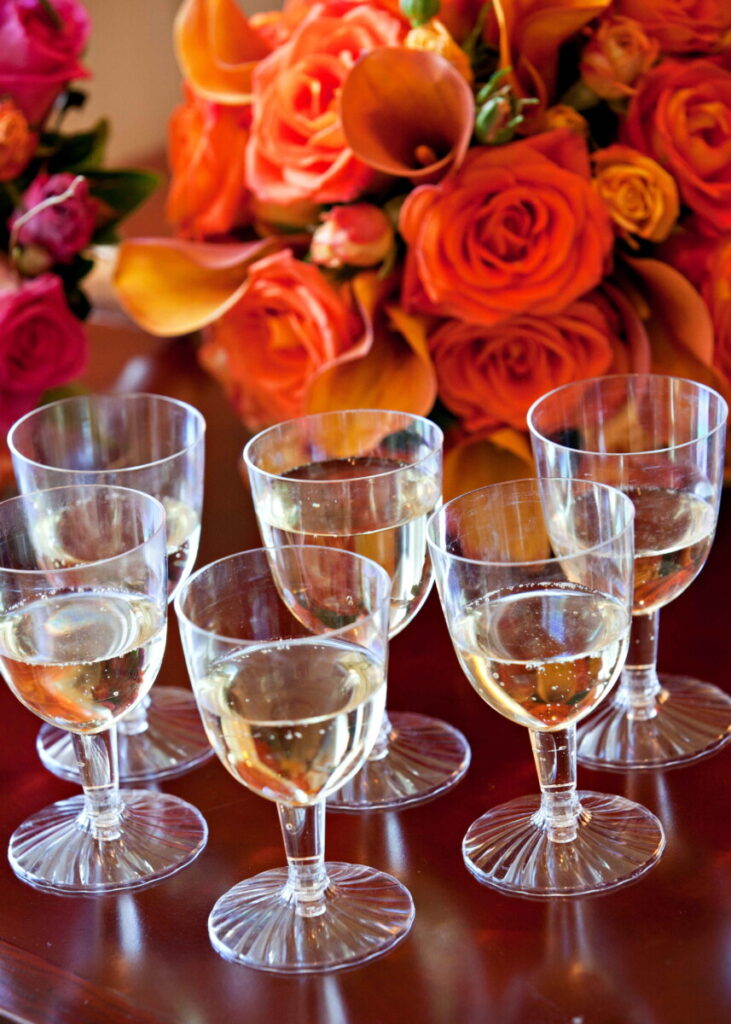 Champagne glasses arranged beside orange and pink wedding flowers