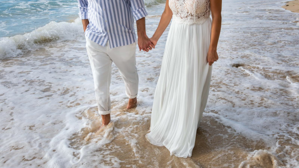 Couple walking hand in hand through the surf on a Barbados beach