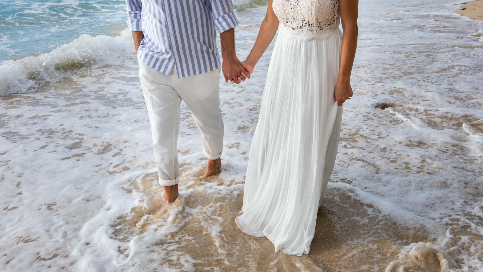 Couple walking hand in hand through the surf on a Barbados beach