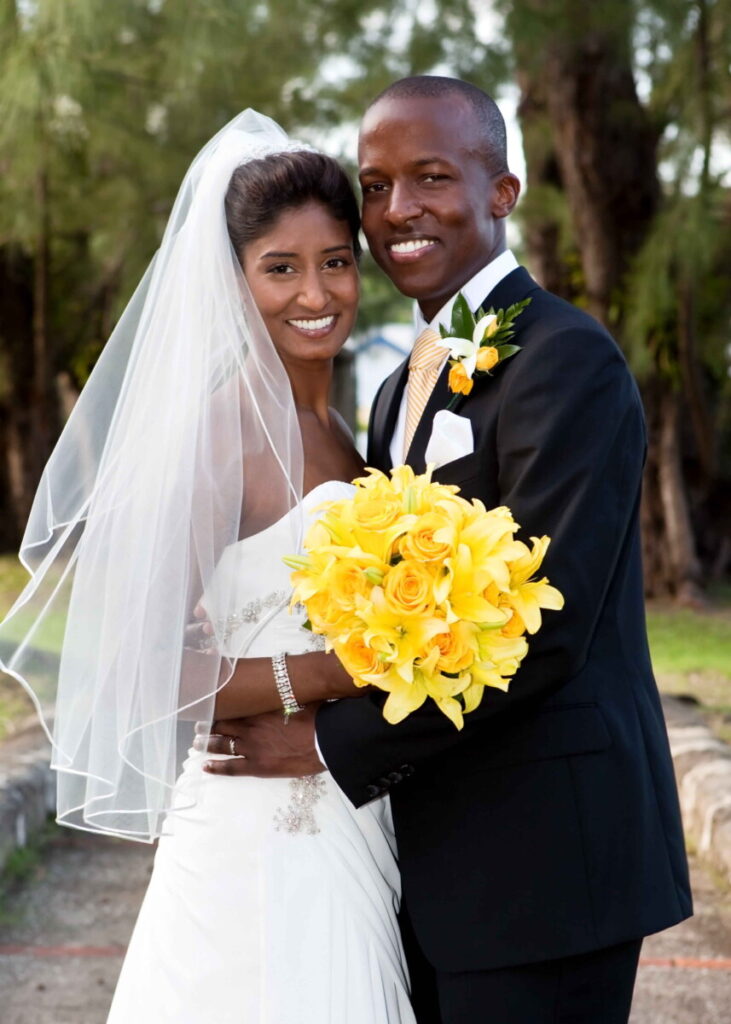 Newlyweds posing together with a bright yellow wedding bouquet